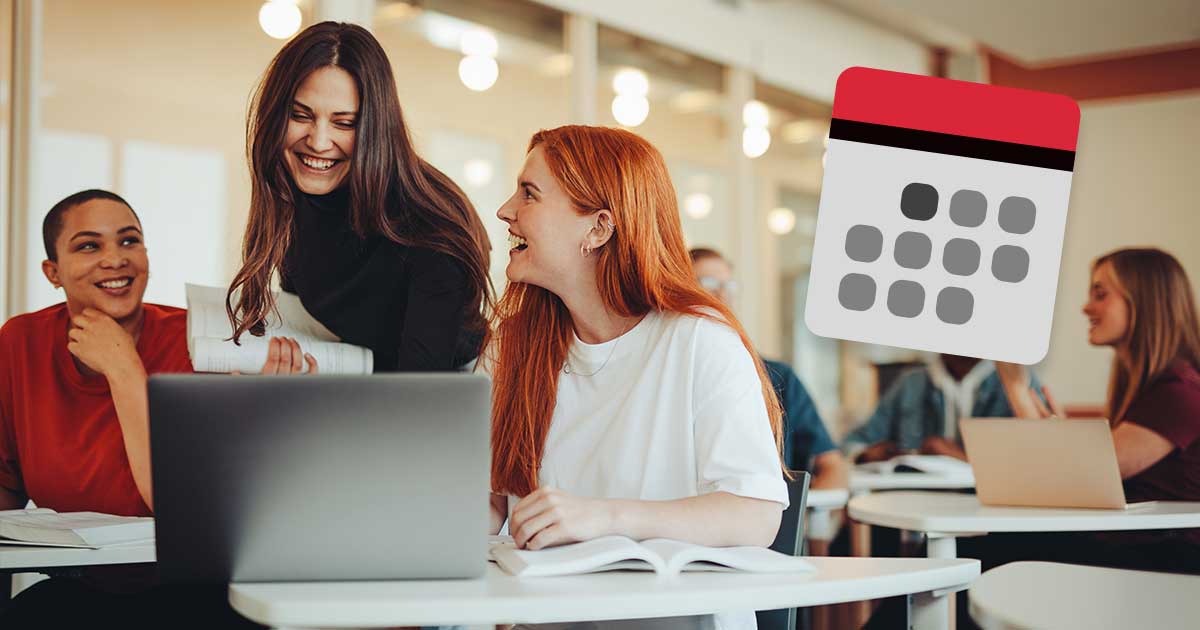 Drei junge Frauen versammeln sich um einen Tisch und schauen auf einen Laptop.