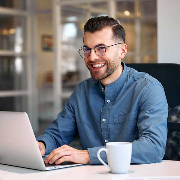 Junger Mann sitzt am Schreibtisch mit Laptop.