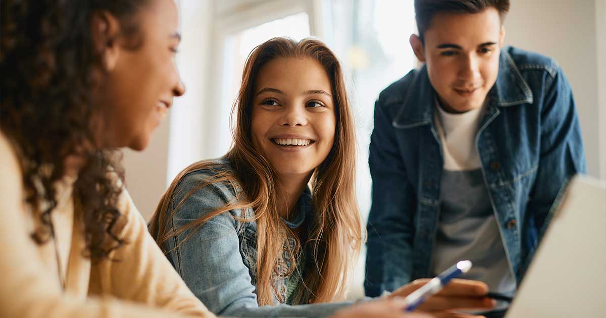 Eine Gruppe von Schüler(inne)n schauen auf einen Laptop