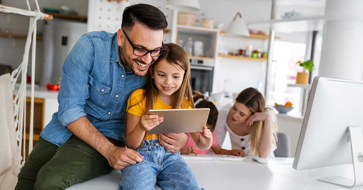 Vater schaut mit seiner Tochter auf ein Tablet